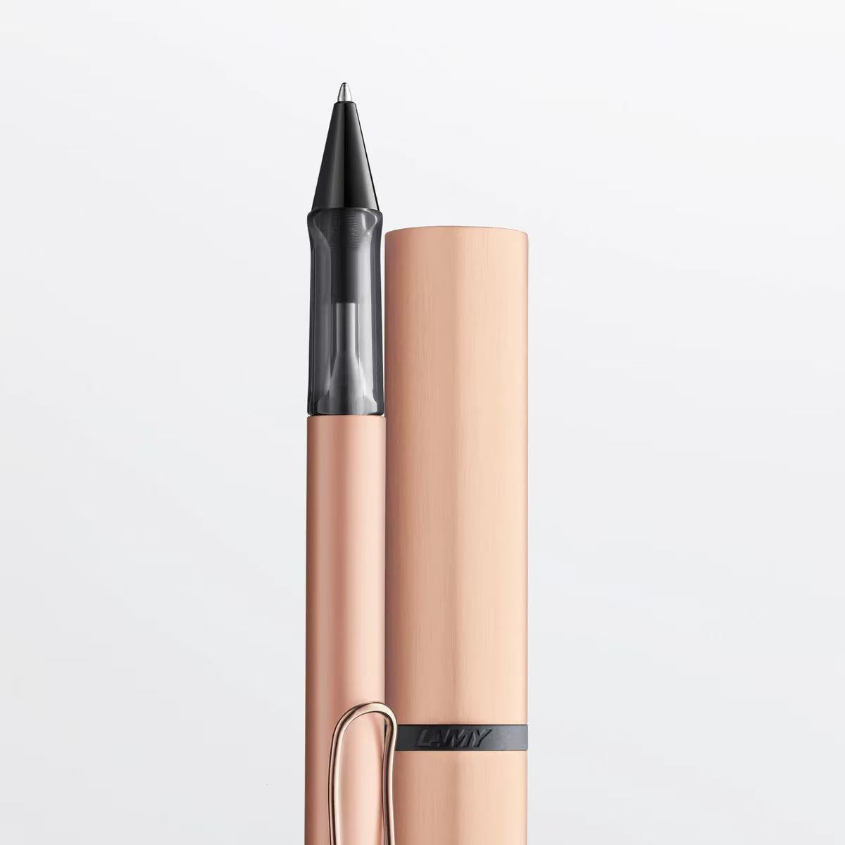 Rose gold pen with black cap on a light gray background