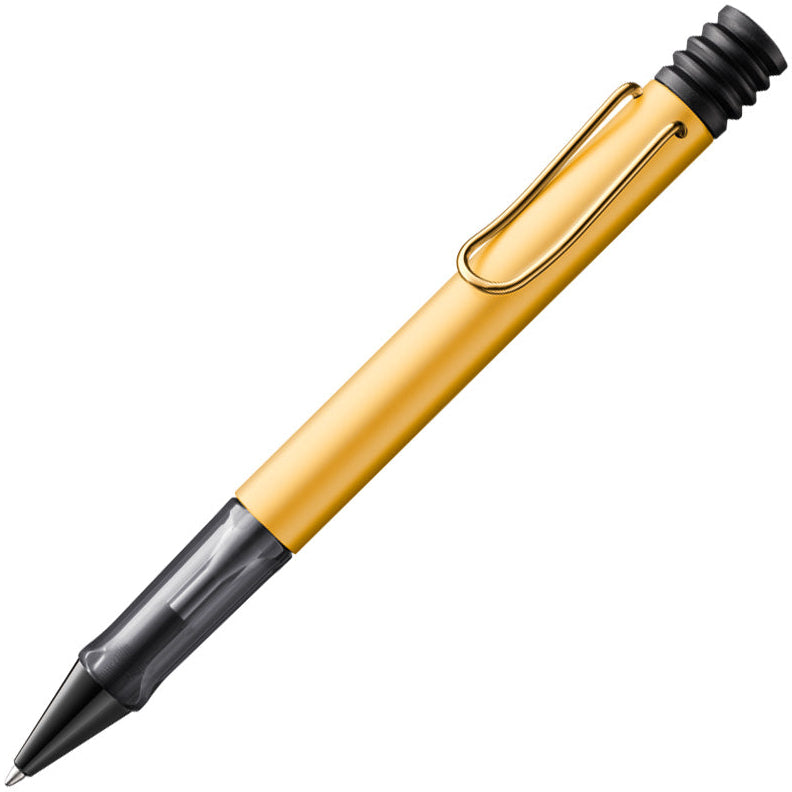 A yellow LAMY Lx ballpoint pen with a transparent handle and metal clip, shown with the tip pointed towards the top of the image.
